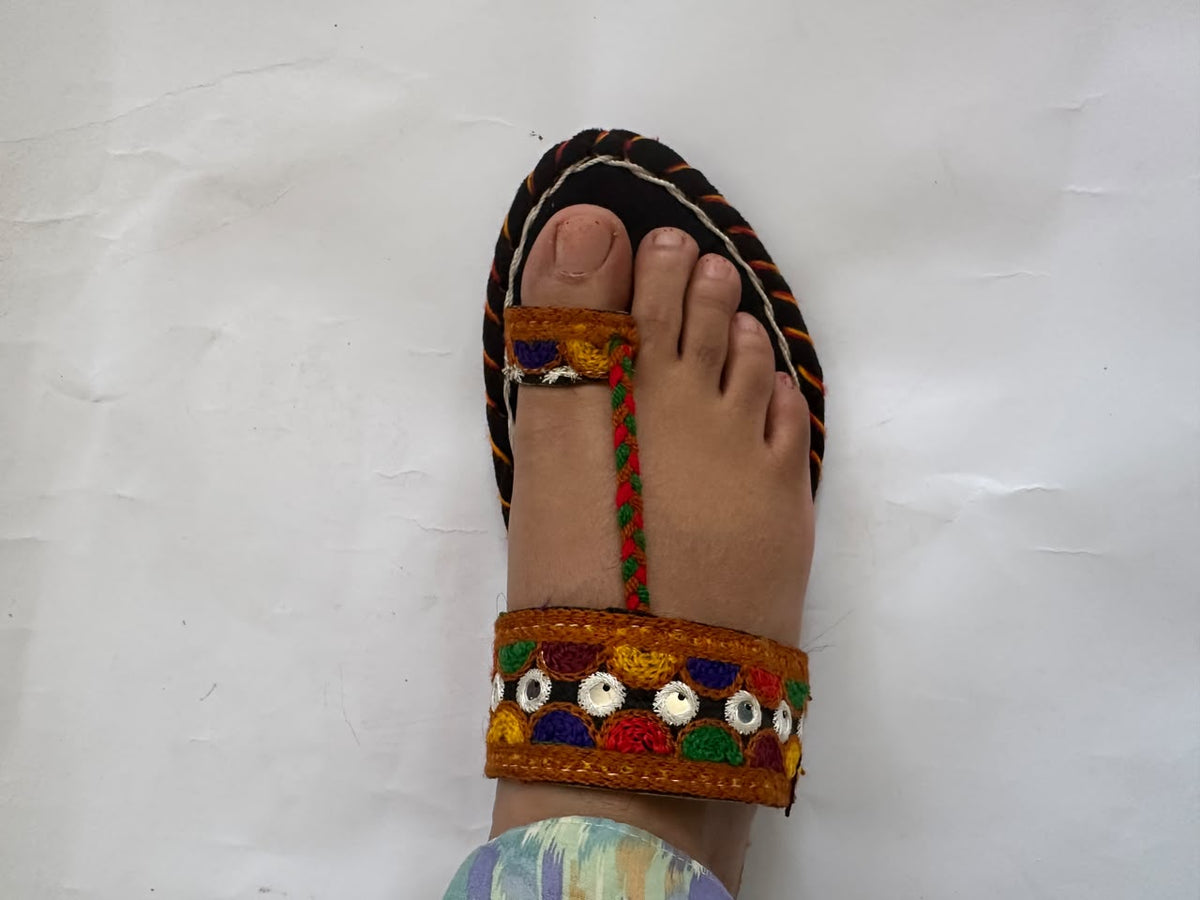 Embroidered Balochi chappal with mirror work and toe loop worn on foot – top view