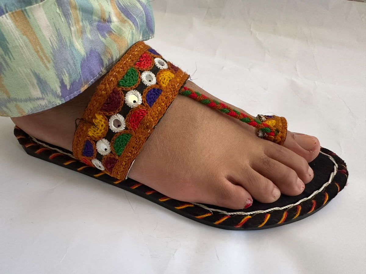 Woman wearing a handmade Balochi chappal with mirror work embroidery and braided toe strap – side view